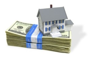 A home on a stack of cash, signifying home buying